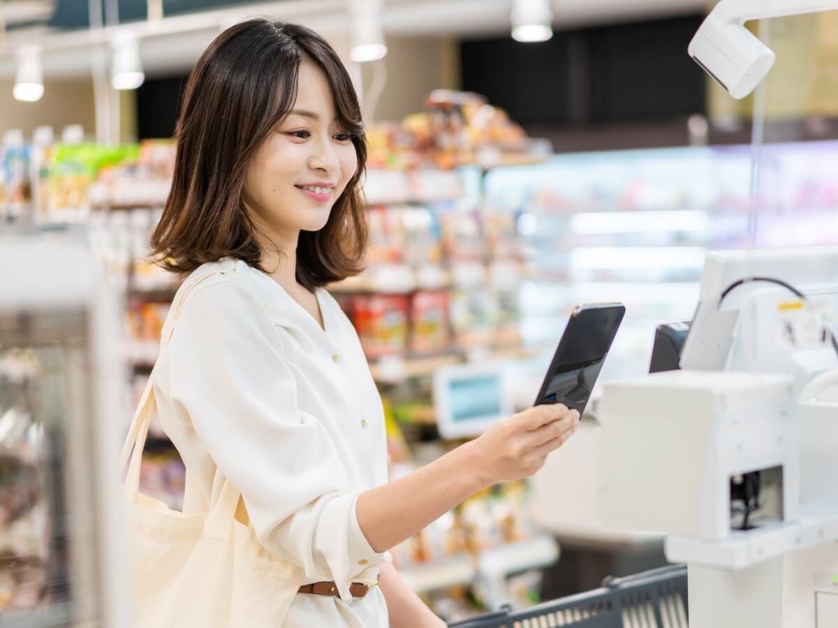画像:スマホを片手に画面を確認している女性