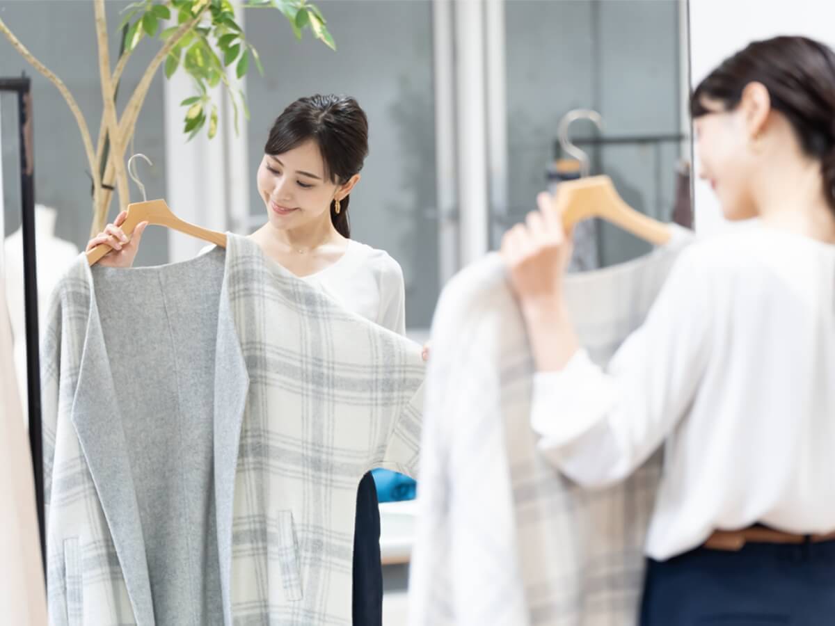 画像:洋服を持って鏡の前にいる女性